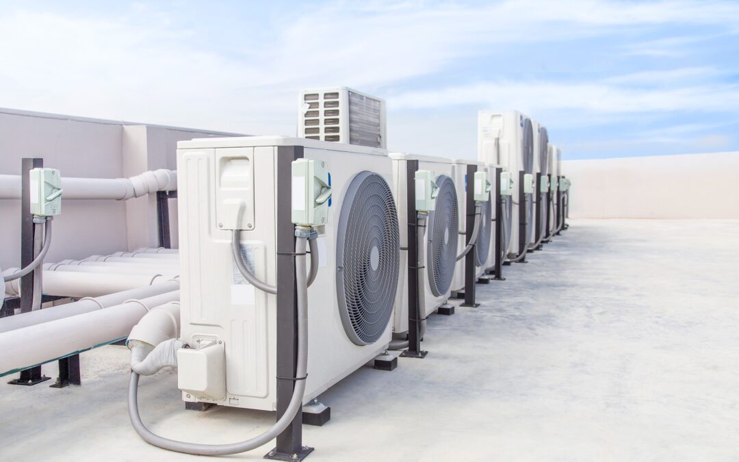 A row of white air conditioning units on the roof of a commercial building.